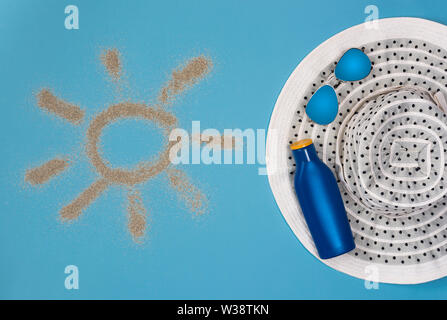 Dipinto di sun, cappello, crema solare e occhiali da sole su sfondo blu. Vista dall'alto. Tema la spiaggia su sfondo blu. Foto Stock