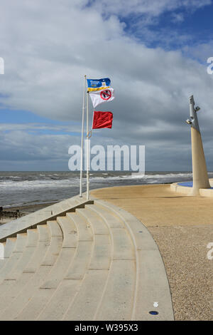 Cemento a gradini e passeggiata con tre bandiere di allarme sui pali di bandiera che tremano nella brezza in cleveleys lancashire uk Foto Stock