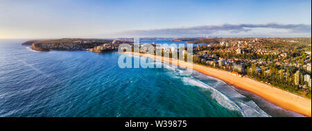 Lunga striscia di pulire il giallo sabbiosa spiaggia di Manly - parte di Sydney famose spiagge del nord visto dalla metà di aria con lontano porto di Sydney e Manly acqua Foto Stock