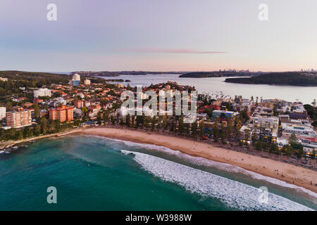 Manly Beach sabbia pulita da laminati surf onde con frequentatori di spiaggia e surfisti a tranquillo tramonto sulla città di Sydney e distante dal porto. Foto Stock