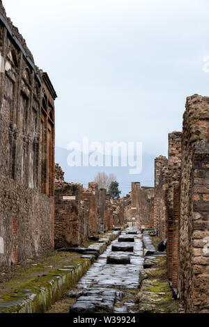 Un antica strada romana con ruota di carrello di solchi e una diga di Pompei, Italia Foto Stock