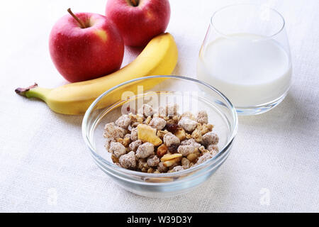 Il cibo sano con fiocchi di mais cereale in una ciotola, mela, banana e vetro con il latte. La colazione del mattino. Foto Stock