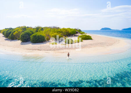 Giovane su una spiaggia tropicale con acqua blu e palme - Coron, Filippine Foto Stock
