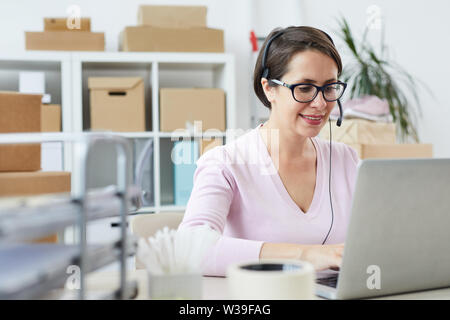 Felice operatore helpdesk parlando nel microfono delle cuffie mentre la consulenza clienti online Foto Stock