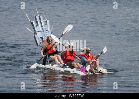 Membri del latte dei troni di team in gara nella categoria adulti della Seafair cartone di latte Derby a Seattle, Washington, il 13 luglio 2019. La barca annuale gara è stato tenuto dal 1972 come parte di Seattle iconici Seafair celebrazione. I partecipanti hanno il compito di costruire una human powered natante con un minimo di 50 vuoto, uno-mezzo gallone di latte cartoni. Foto Stock