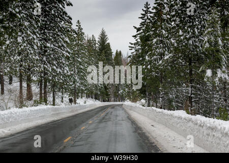 Strada di Montagna autostrada 88 verso Carson Pass, California, Stati Uniti d'America, in un giorno di inverni con la neve sul lato della strada come un segno di guida pericolosa Foto Stock