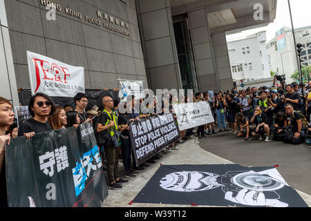 Hong Kong, Cina. 14 Luglio, 2019. Silent marzo a Hong Kong per fermare la violenza della polizia e di difendere la libertà di stampa vede lavorare premere, gli studenti di giornalismo e i loro educatori sia il passato e il presente si riuniscono per protestare. I manifestanti al di fuori della sede della polizia. La folla ha indossato tutto nero in segno di solidarietà. Credito: Jayne Russell/Alamy Live News Foto Stock