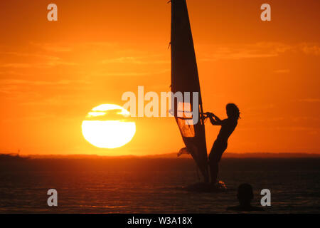 Un windsurf vela verso il tramonto sulla Port Phillip Bay Melbourne. Foto Stock