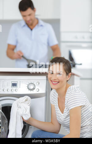 Donna sorridente tenendo panni dalla macchina di lavaggio Foto Stock