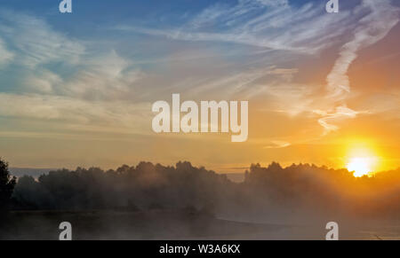 Tramonto su un piccolo lago con la nebbia sopra l'acqua. Foto Stock