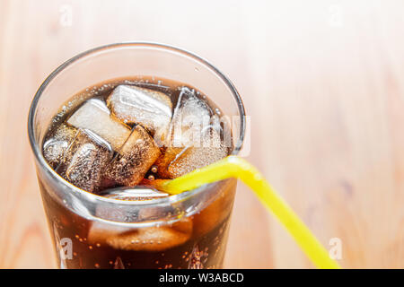 Icy bevanda fredda in un bicchiere e ravvicinata. Bicchiere di fresca bevanda frizzante con ghiaccio su una tavola di legno, shot dettagliati Foto Stock