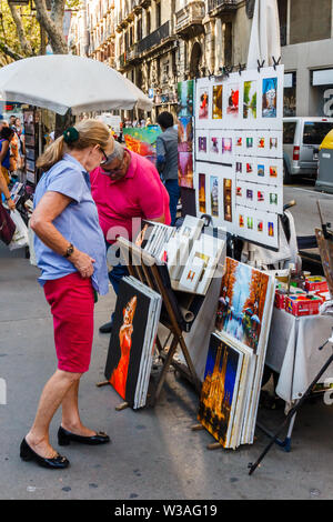 Barcellona, Spain-September 5° 2015: Senior donna guardando i dipinti in vendita su una delle Ramblas. Le ramblas sono famose strade dello shopping. Foto Stock