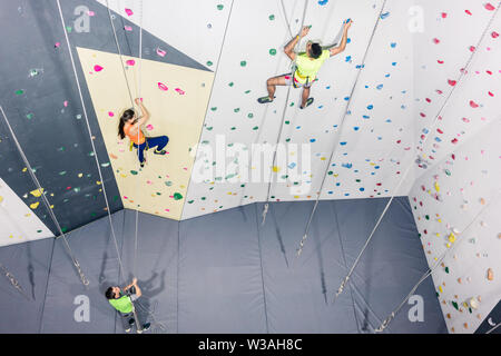 Athletic gente pratica parete di roccia arrampicata Foto Stock