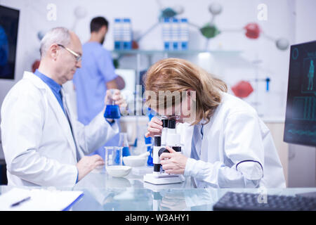 Femmina Senior scienziato che lavora in un laboratorio contro le malattie. Senior Scientist maschio con una provetta in mano. Foto Stock