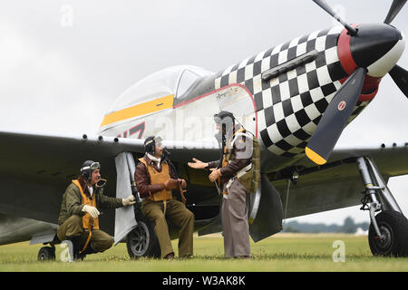 Re-enactors dagli Angeli sulla nostra ali, una seconda guerra mondiale rievocazione gruppo, stand by TF-51D Mustang 'contrario Maria' durante il Flying Legends Air Show a IWM Duxford. Foto Stock