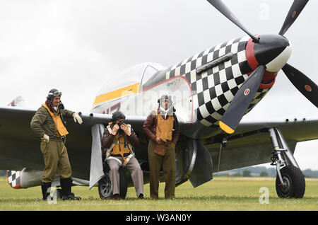 Re-enactors dagli Angeli sulla nostra ali, una seconda guerra mondiale rievocazione gruppo, stand by TF-51D Mustang 'contrario Maria' durante il Flying Legends Air Show a IWM Duxford. Foto Stock