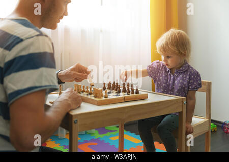 Brain games - padre insegna a giocare a scacchi per il suo bambino a casa Foto Stock