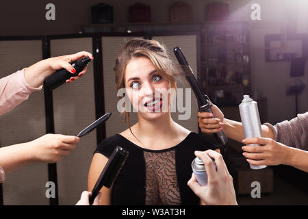 Modello di gioiosa circondato da mani con prodotti da trucco Foto Stock