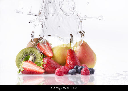 Un ondata di acqua chiara cadere sui diversi e colorati frutti su sfondo bianco Foto Stock