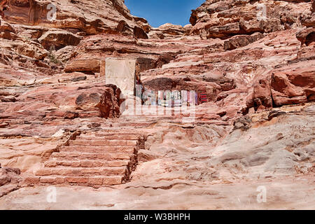 Una serie di gradini di pietra scolpiti nel pavimento del siq conduce il canyon stretto passato una serie di piccoli negozi al monastero di Petra. Foto Stock