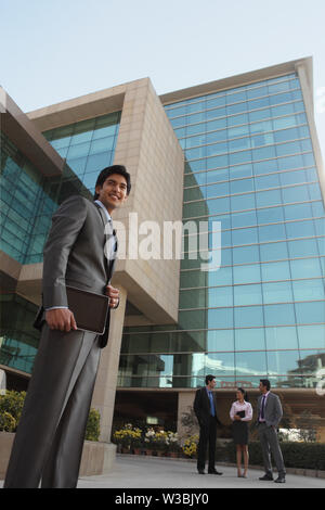 Vista ad angolo basso di un uomo d'affari in piedi con tablet digitale Foto Stock