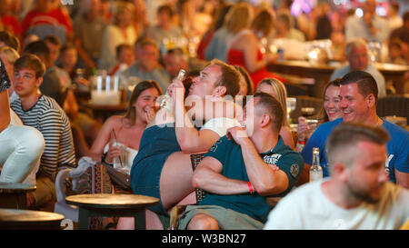 Turisti di passaggio le loro vacanze a Magaluf incontrano per guardare su giganteschi schermi televisivi la Champions League Soccer Fin Foto Stock