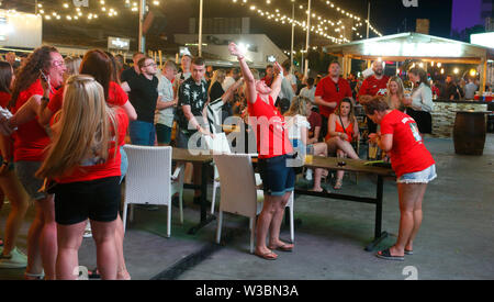 Turisti di passaggio le loro vacanze a Magaluf incontrano per guardare su giganteschi schermi televisivi la Champions League Soccer Fin Foto Stock