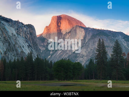 Parco Nazionale di Yosemite vista di mezza cupola dalla valle durante il tramonto colorato con alberi e rocce. In California, Stati Uniti d'America Foto Stock