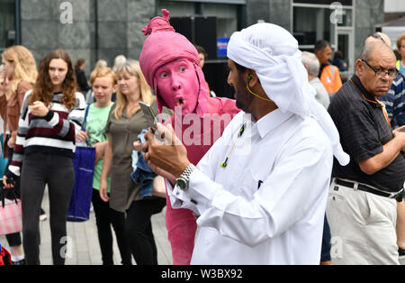 Gli artisti di strada si mescolano con i membri del pubblico nell'area Bullring di Birmingham. Gli spettacoli facevano parte dell'annuale Summer in Southside Arts Festival. Foto Stock