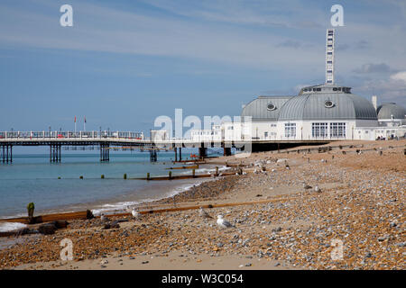 WORTHING, Regno Unito - 13 luglio 2019: Mare i gabbiani sono seduti sulla spiaggia pebbel davanti di art deco pier a Worthing Foto Stock