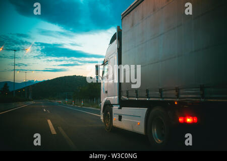 Autocarro in auto sulla strada in serata. Trasporto con autocarro cargo. Il trasporto e la spedizione. La velocità e il concetto di consegna. In viaggio o in viaggio e wanderlust. Foto Stock
