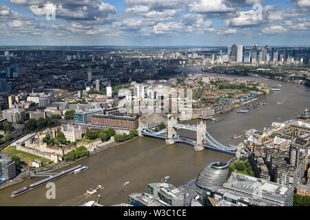 Vista aerea del fangoso Fiume Tamigi con torre del castello di Londra, il Tower Bridge, curvo moderno City Hall e da Canary Wharf grattacieli London Inghilterra England Foto Stock