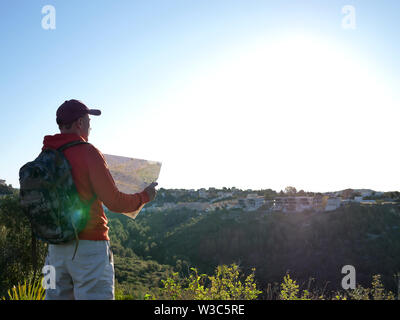 Tourist è considerato una mappa, si erge contro lo sfondo della città sulla collina Foto Stock