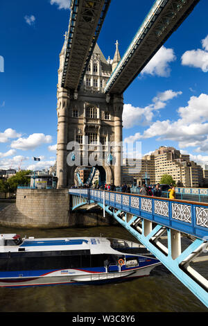 Il Tower Bridge attraverso il Tamigi a Londra con il camminamento superiore e il pavimento in vetro e in barca passando sotto il ponte mobile Foto Stock