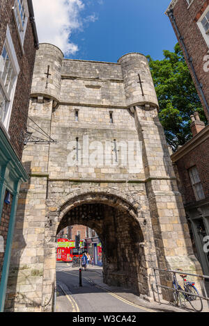 Bootham Bar, York. Un antico ingresso della città in piedi alla fine di una strada. I negozi sono su ogni lato e un tourbus è visibile attraverso il passaruota. Foto Stock