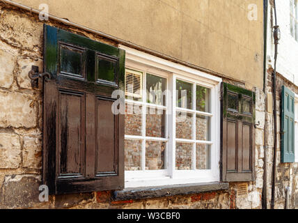 Una vecchia finestra ritagliata in York. La finestra è impostata in un muro di pietra e una parte di York Minster si vede nella riflessione. Foto Stock