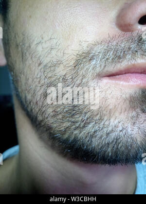 Barbuto giovane uomo, stoppia vicino a. Barba lunga più di una settimana. Capelli sulla faccia di un uomo, una barba corta. Foto Stock