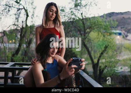 Due giovani donne prendere un selfie sul balcone la sera Foto Stock