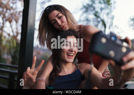 Due giovani donne prendere un selfie sul balcone la sera Foto Stock