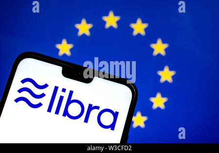 Facebook Libra crypto logo valuta sullo smartphone e sfocata bandiera dell'UE in una schermata di un laptop sullo sfondo. Foto concettuale. Foto Stock