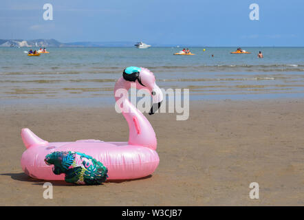 Rosa fenicottero gonfiabile sulla spiaggia di Weymouth Regno Unito Foto Stock