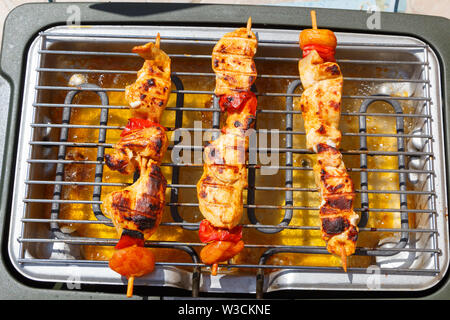Tre marinato spiedino di pollo sulla griglia di un barbecue elettrico Foto Stock