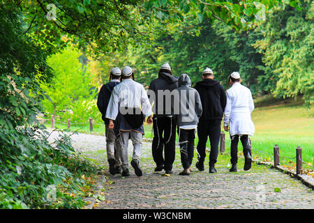 Giovane ebreo Hasidic uomini stanno camminando in Uman, Ucraina. Gli Ebrei religiosi. Sulle loro teste hanno pila, con le parole in ebraico Na Nah Nahma Nachman Foto Stock