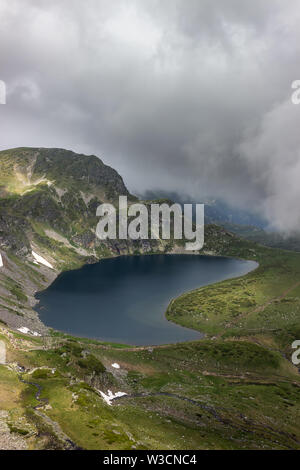 Misty, drammatico, moody vista del famoso lago di rene sulla montagna Rila in Bulgaria e soleggiati altopiani rocciosi Foto Stock