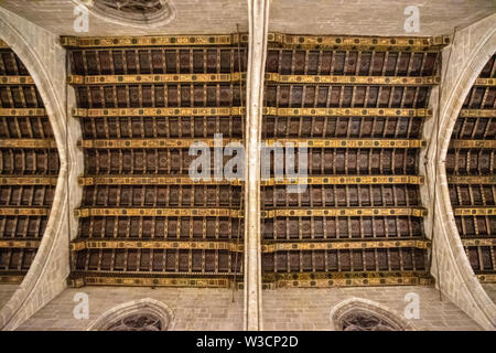 Guardando verso l'alto un puntone di legno soffitto con archi di pietra da una cattedrale di Barcellona, Spagna Foto Stock