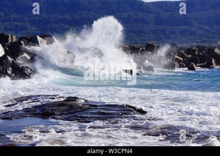 Onde che si infrangono sulle rocce Foto Stock