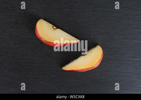Gruppo di due fette di fresco rosso scuro pera anjou flatlay sulla pietra grigia Foto Stock