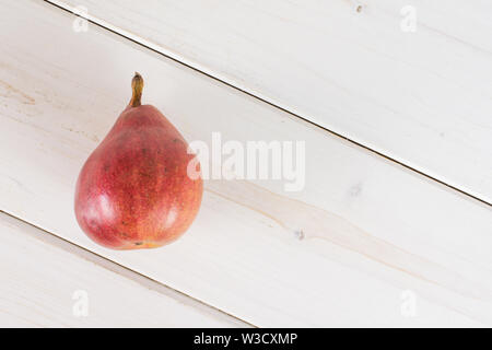 Un intero fresco rosso scuro pera anjou flatlay su legno bianco Foto Stock