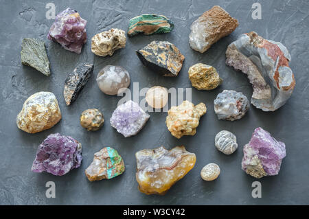 Pietre minerali collezione: turchese, morion, quarzo fumè, strass, calcedonio, Agata, ametista, onice, calcedonio sul cemento grigio Sfondo. A Foto Stock