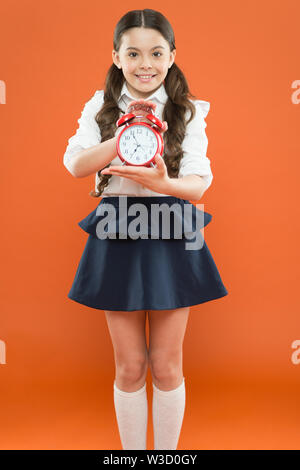 Il tempo di studio. Le lezioni cominciano. Sviluppare la disciplina. Tempo di pausa e di relax. Tempo di vacanza. Scuola elementare campana giorno pianificazione. Concetto Schooltime. Schoolgirl bambino uniforme formale di tenere premuto il tasto alarm clock. Foto Stock